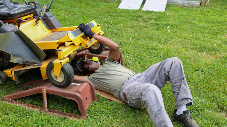 Man working on the deck of a riding lawn mower