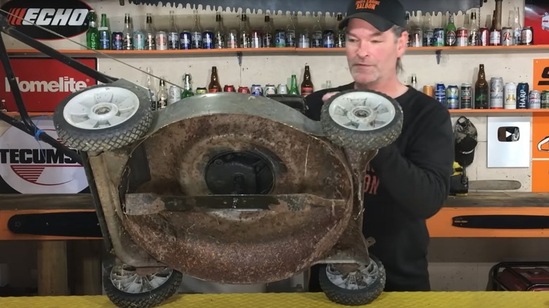 Man working on a bent push mower blade