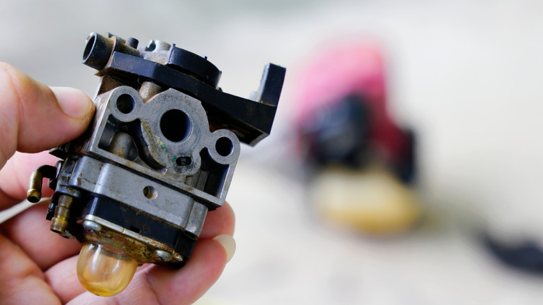 Person holding a carburetor