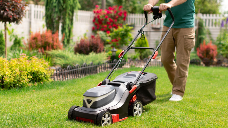 A man operating a black and grey lawn mower