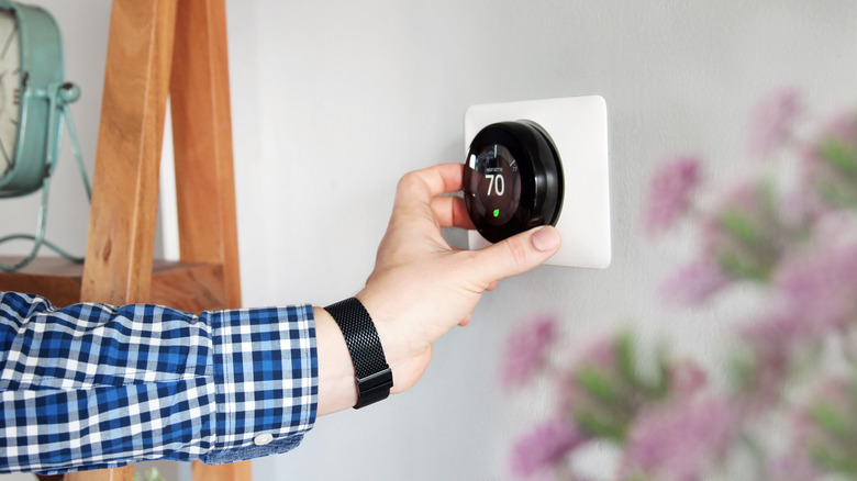 Someone adjusting the temperature of a thermostat