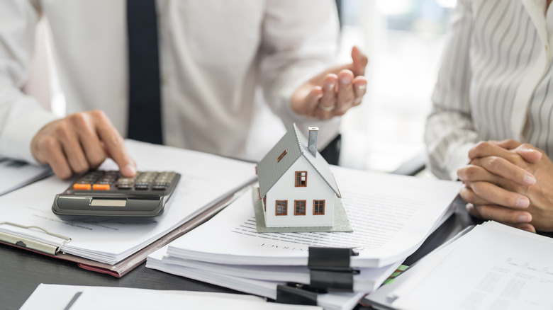 Two people working on a real estate transaction with paperwork and calculator