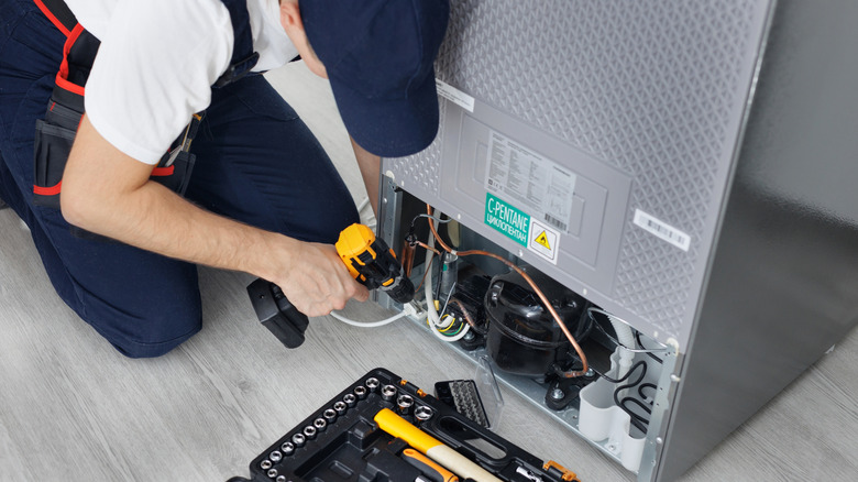handyman working on fridge
