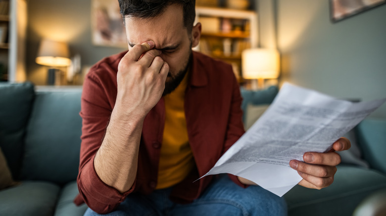 A frustrated man rubs his head after looking at a utility bill