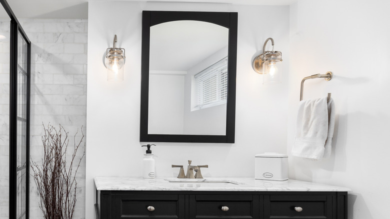 Wall sconces mounted to the wall on either side of a bathroom vanity mirror