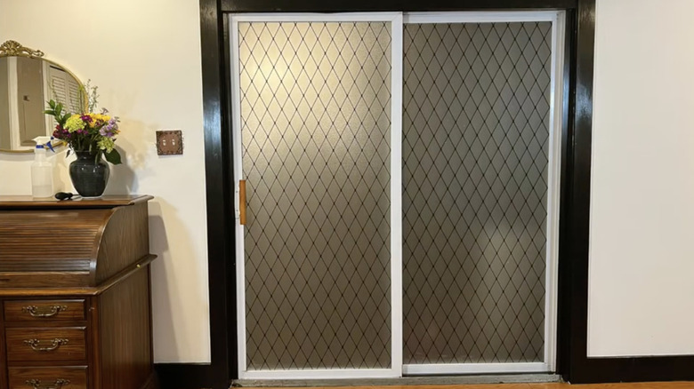 Velimax black lattice film installed on an indoor sliding glass door with a black frame.