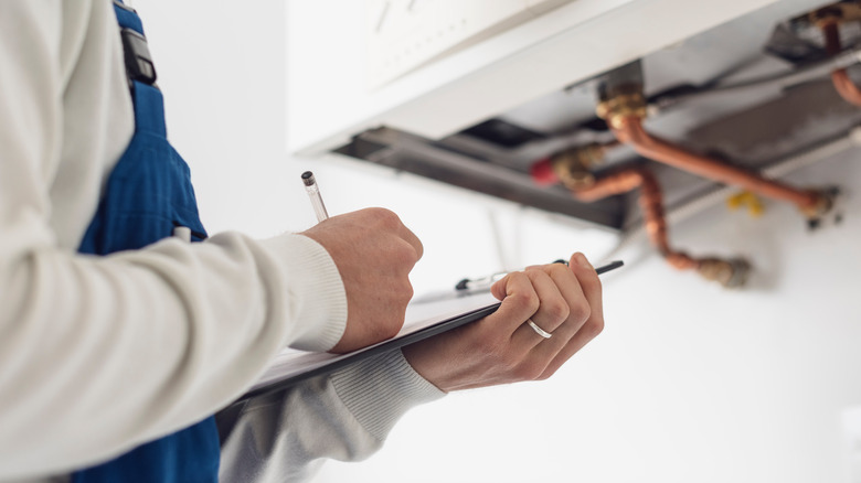 professional technician writing on clipboard