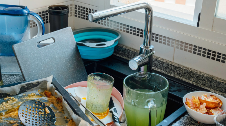 A sink and countertop overflowing with dirty dishes