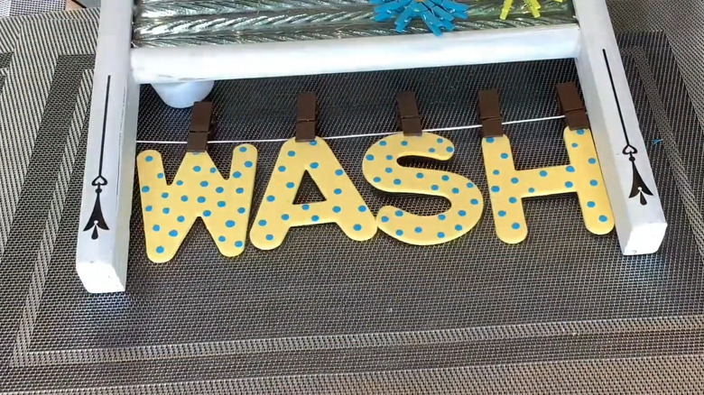 a mini faux clothesline between a washboard's legs with hanging letters spelling "WASH"