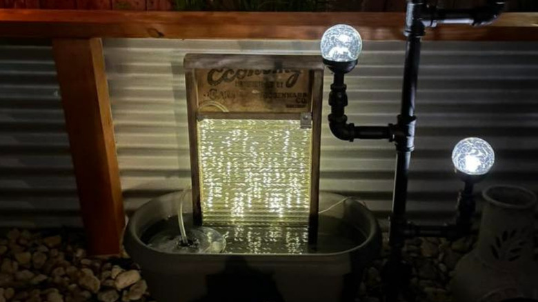 an antique washboard and metal tub turned into a water feature in a backyard
