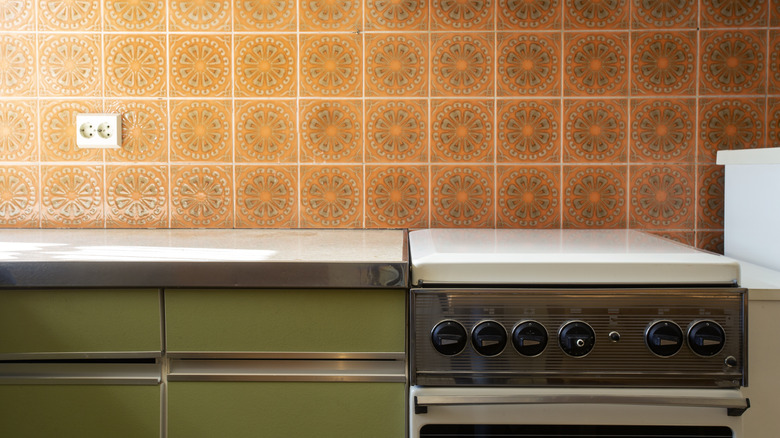 Photo of a retro kitchen with orange tile backsplash and green cupboards