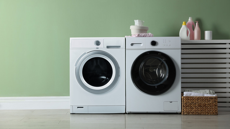 laundry room with washing machine and dryer against a green wall