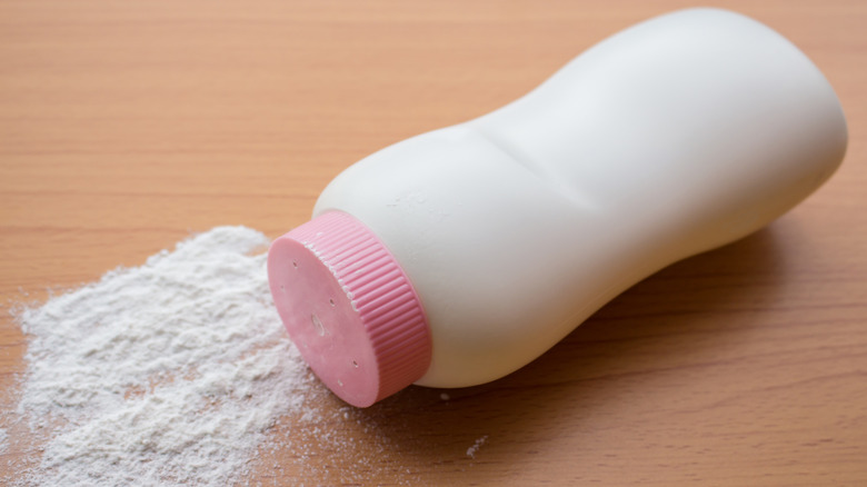 A bottle of talcum powder spilling on a wooden floor