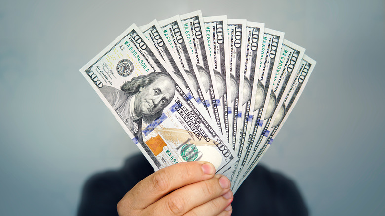 Hand holding hundred dollar bills