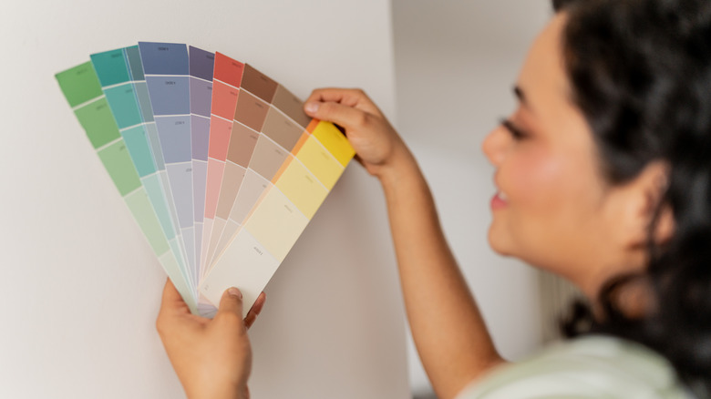 A woman holding up paint samples against a wall