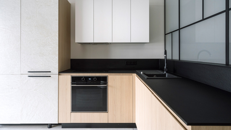 A kitchen with black thin quartz countertops and wood cabinets