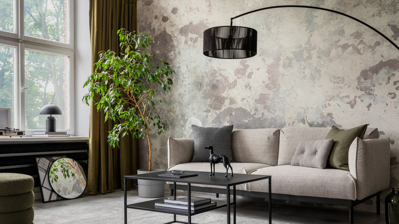 A living room with a gray couch, black coffee table, and neutral patterned wallpaper