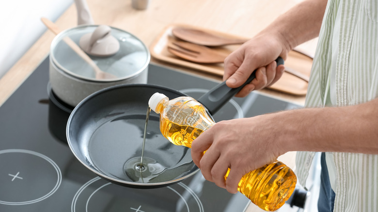 Person pouring cooking oil in pan 