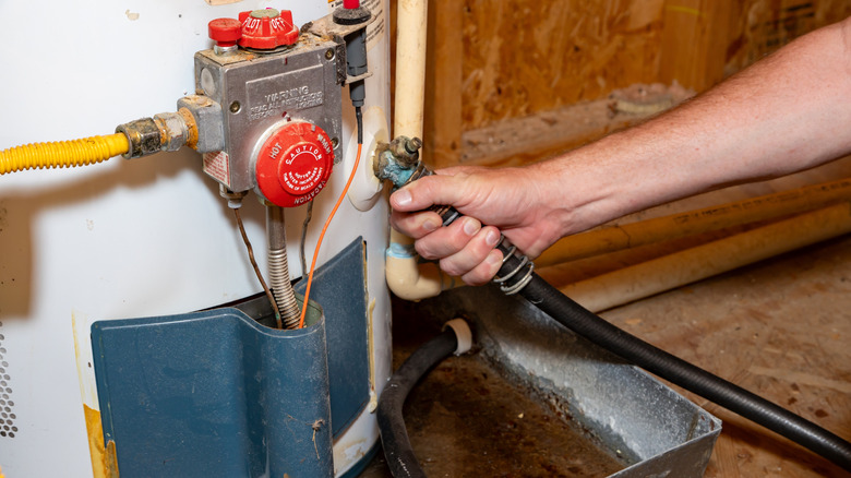 A person connecting a hose to a water heater