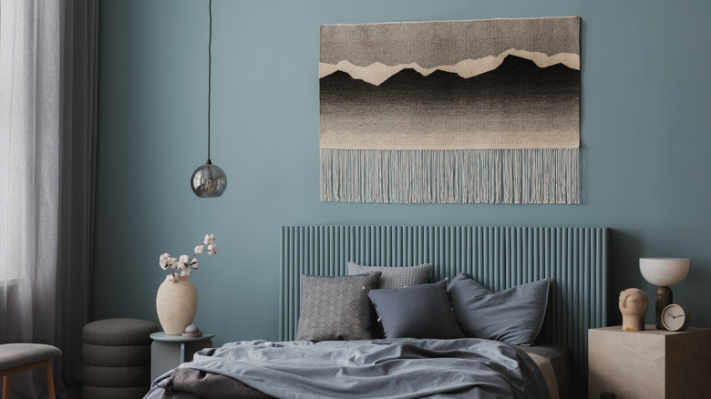 Blue bedroom with neutral tapestry on the wall above the bed