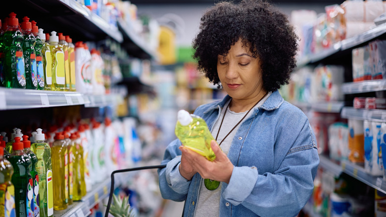 Woman looking at label on cleaning product in grocery store