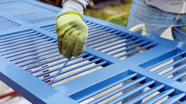 person painting blue window shutters