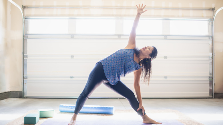 Woman doing yoga in garage on yoga mat