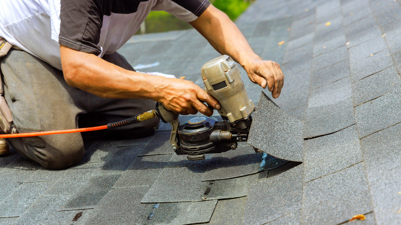 Person installing new shingles on roof