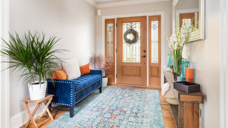 Foyer with blue area rug, blue bench, and wood furniture