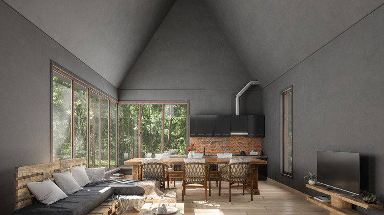A moody sun room with high, vaulted ceilings painted in a monocrhomatic dark gray.