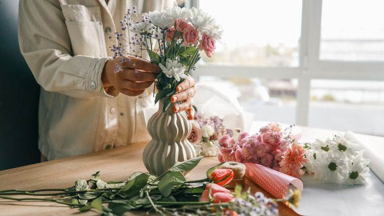woman arranging flowers in a vase on a wooden table
