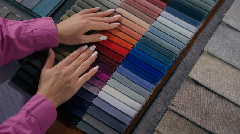 Hands touching fabric swatches in different colors