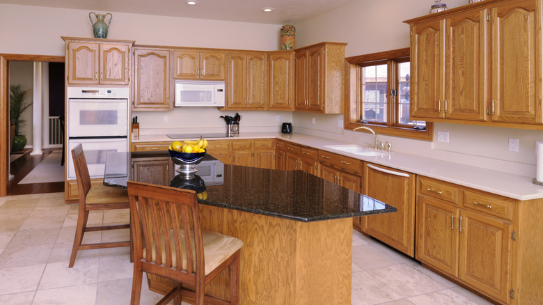 outdated 80s wood kitchen cabinets with dated floor and countertops