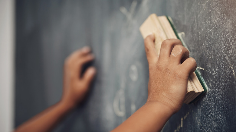 Child cleaning a dusty chalkboard