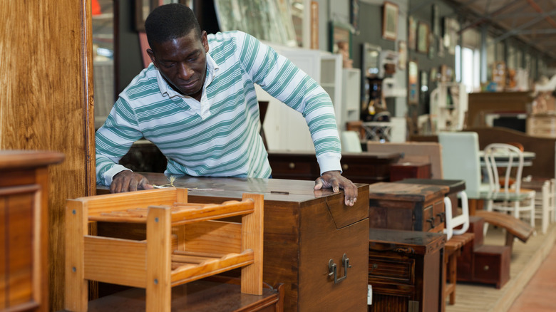 Man looking at antique furnishings in a thrift store