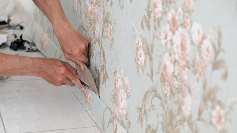 Someone applying floral wallpaper