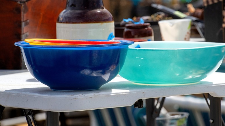 Pyrex blue, orange, and red nesting bowls sit next to an aqua Pyrex bowl at a secondhand market