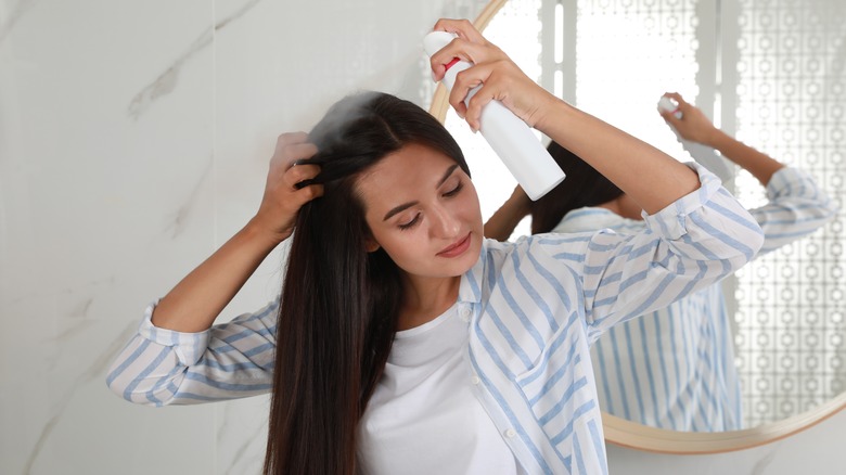 Woman spraying hairspray in bathroom