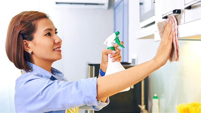 Person disinfecting kitchen cabinets