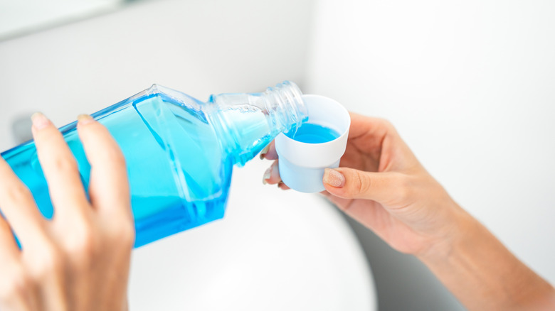 Closeup of person's hands pouring mouthwash into a cap