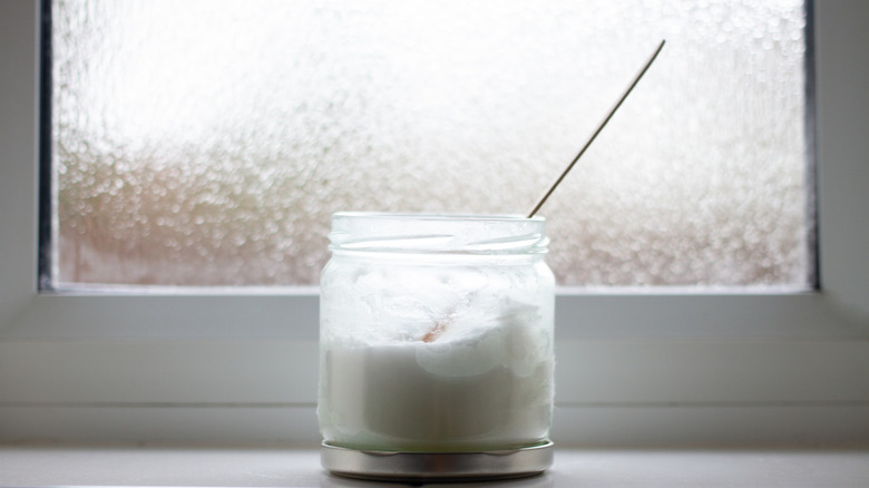 A jar of coconut oil sitting by a bathroom window