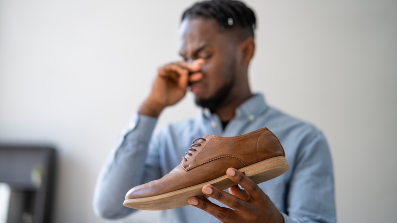 Man holding smelly shoes