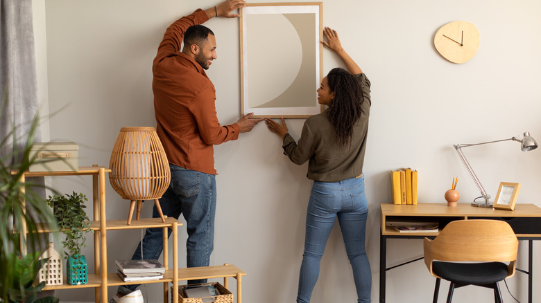 Couple hanging art on the wall