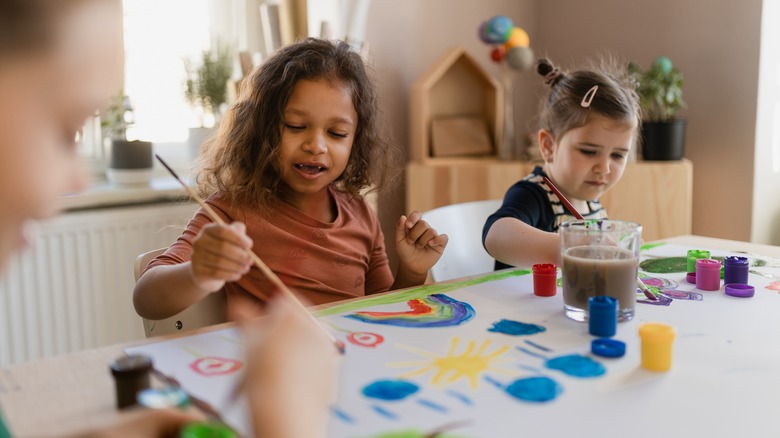 Kids painting pictures at table