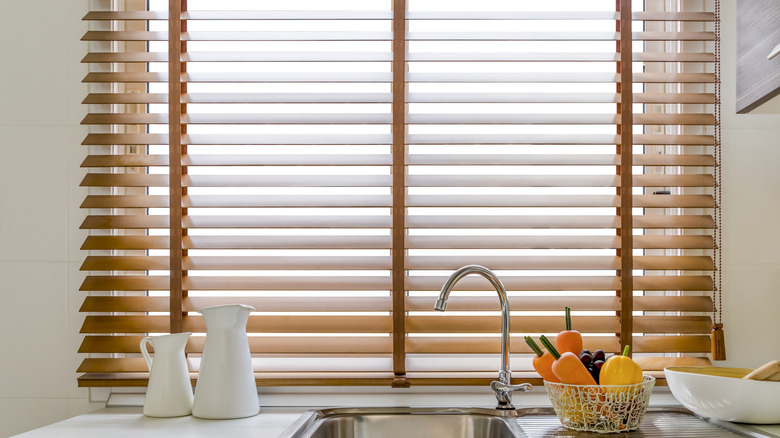 Wood or faux wood blinds in a natural color behind a kitchen sink