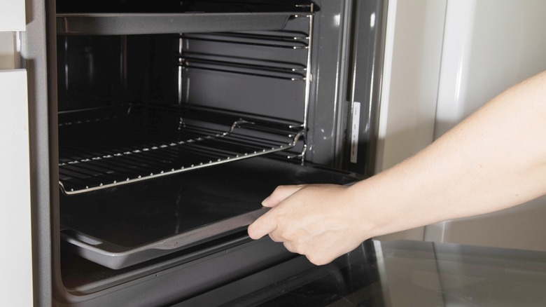 Woman takes baking sheet from oven