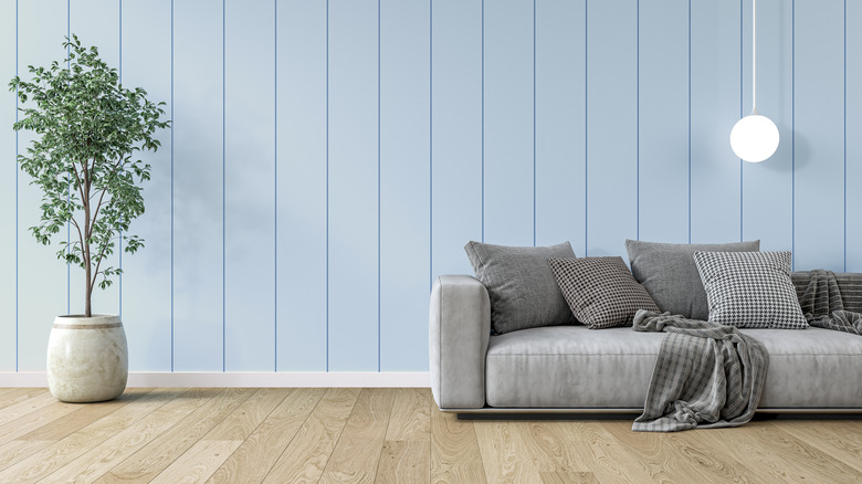 Gray couch in front of powder blue wall of vertical slats and warm brown floor