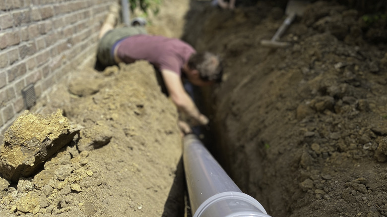 Person adjusting a sewer line in a trench