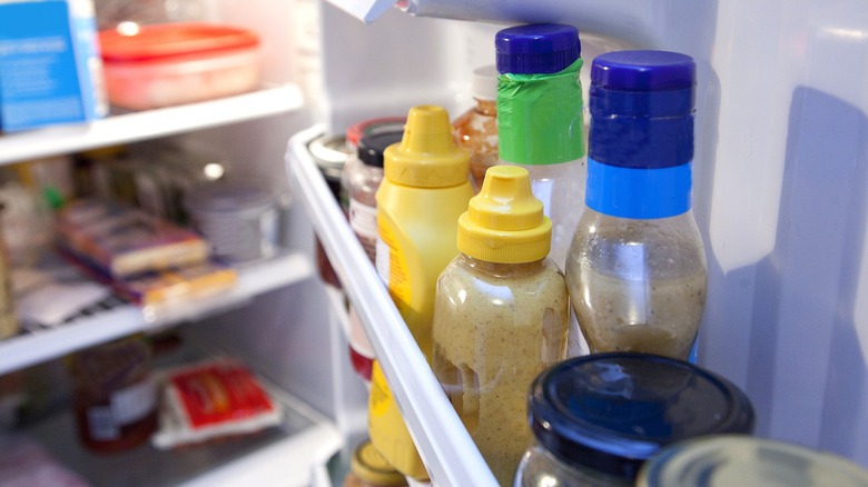 A close-up of condiments on a door shelf inside a refrigerator