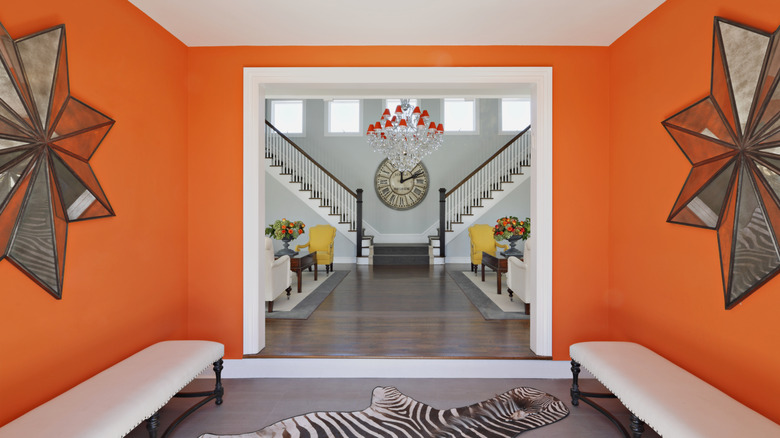 An entryway with bright orange walls, star-shaped wall decor, and two benches